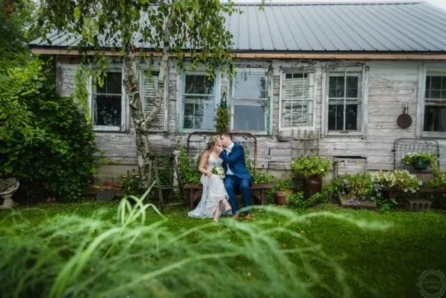 Bride and groom kissing in the hidden garden in front of the rustic chicken coop at Huser Farm