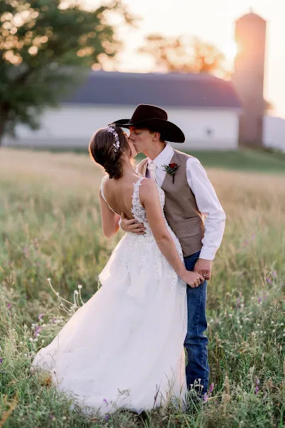 Bride and groom kissing in a field in front of the farm at a Wisconsin country wedding barn