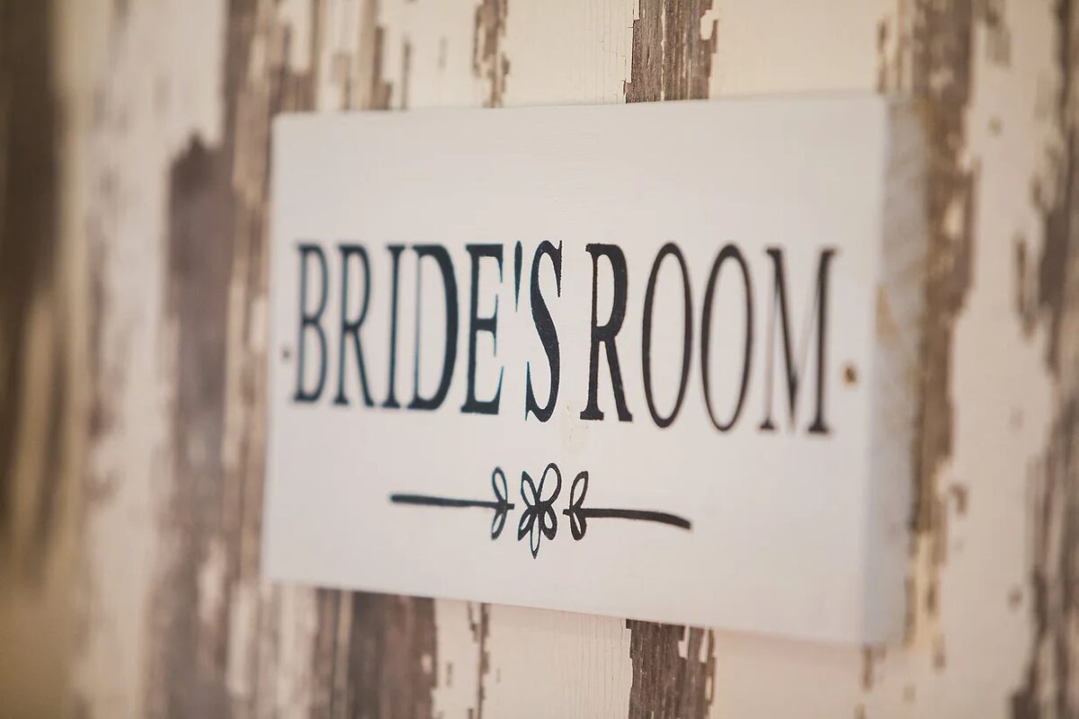 Hand-painted Bride's Room sign on the rustic dressing room door at Huser Farm