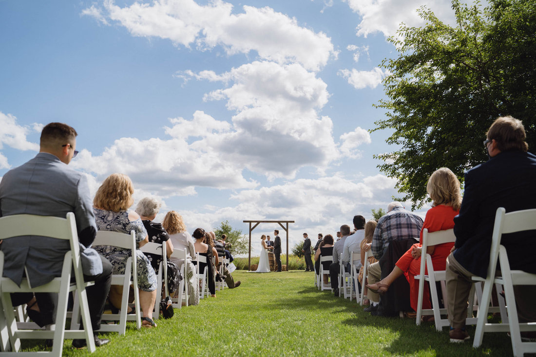 Bride and groom during an outdoor summer wedding ceremony under sun and clouds at Huser Farm wedding barn in Wisconsin